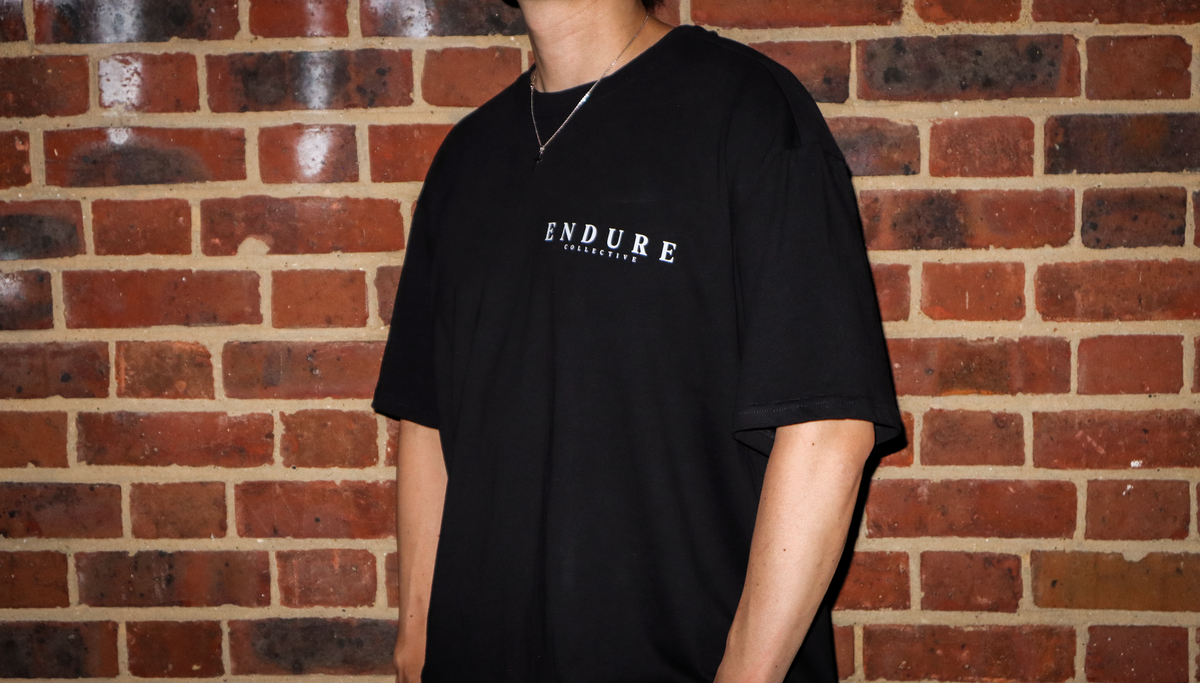 Black Genesis 1:3 oversized T-shirt front fit photo featuring ENDURE COLLECTIVE chest logo and faith-based streetwear design.