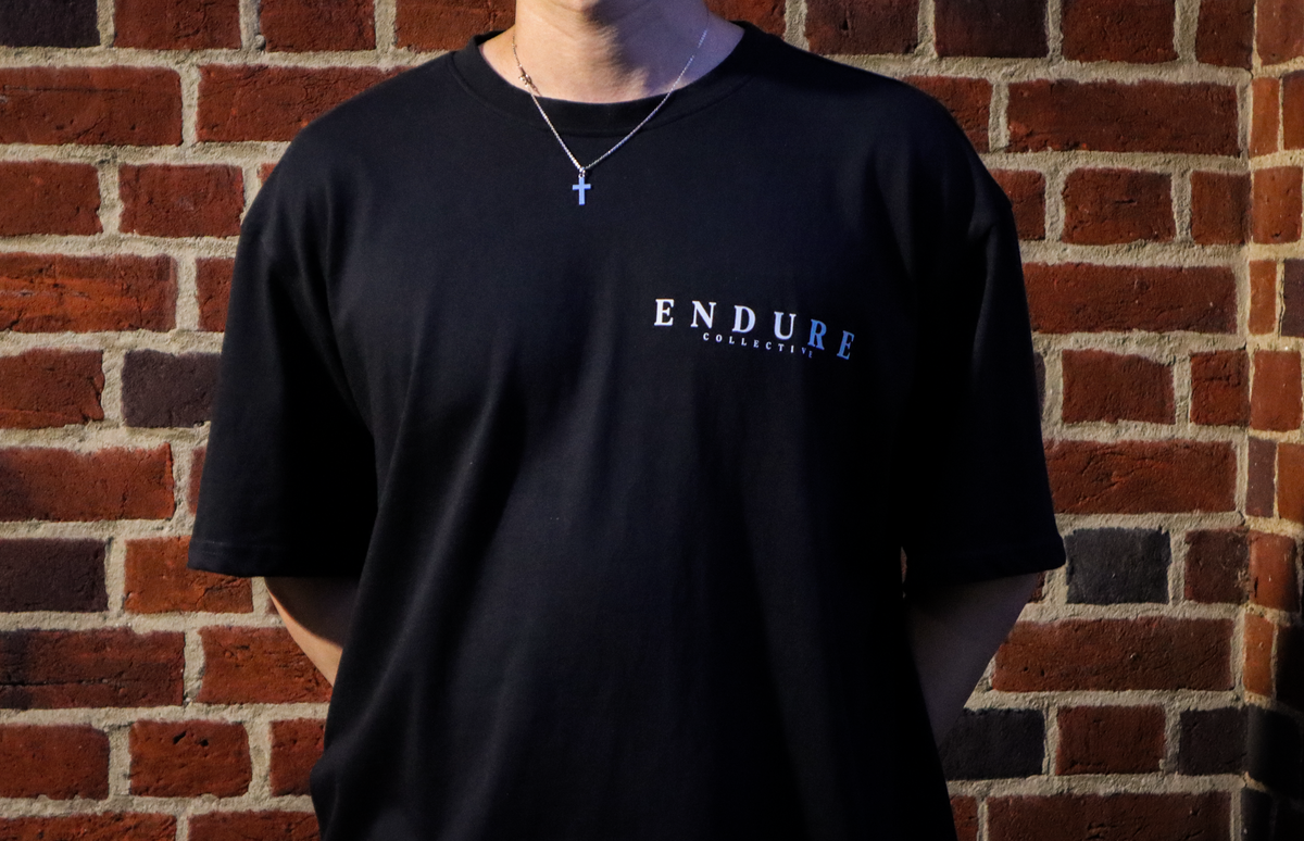 Black Genesis 1:3 oversized T-shirt front logo detail featuring ENDURE COLLECTIVE chest print and scripture-inspired streetwear design.