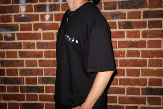 Black Genesis 1:3 oversized T-shirt front logo detail, featuring ENDURE COLLECTIVE chest print and faith-based streetwear design.