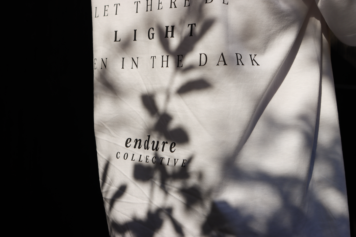 White Genesis 1:3 oversized T-shirt back print detail featuring “Let there be light even in the dark,” faith-based streetwear by ENDURE COLLECTIVE.