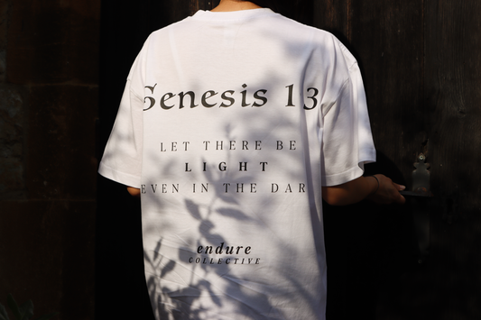 White Genesis 1:3 oversized T-shirt with black back print, featuring “Let there be light even in the dark” by ENDURE COLLECTIVE.